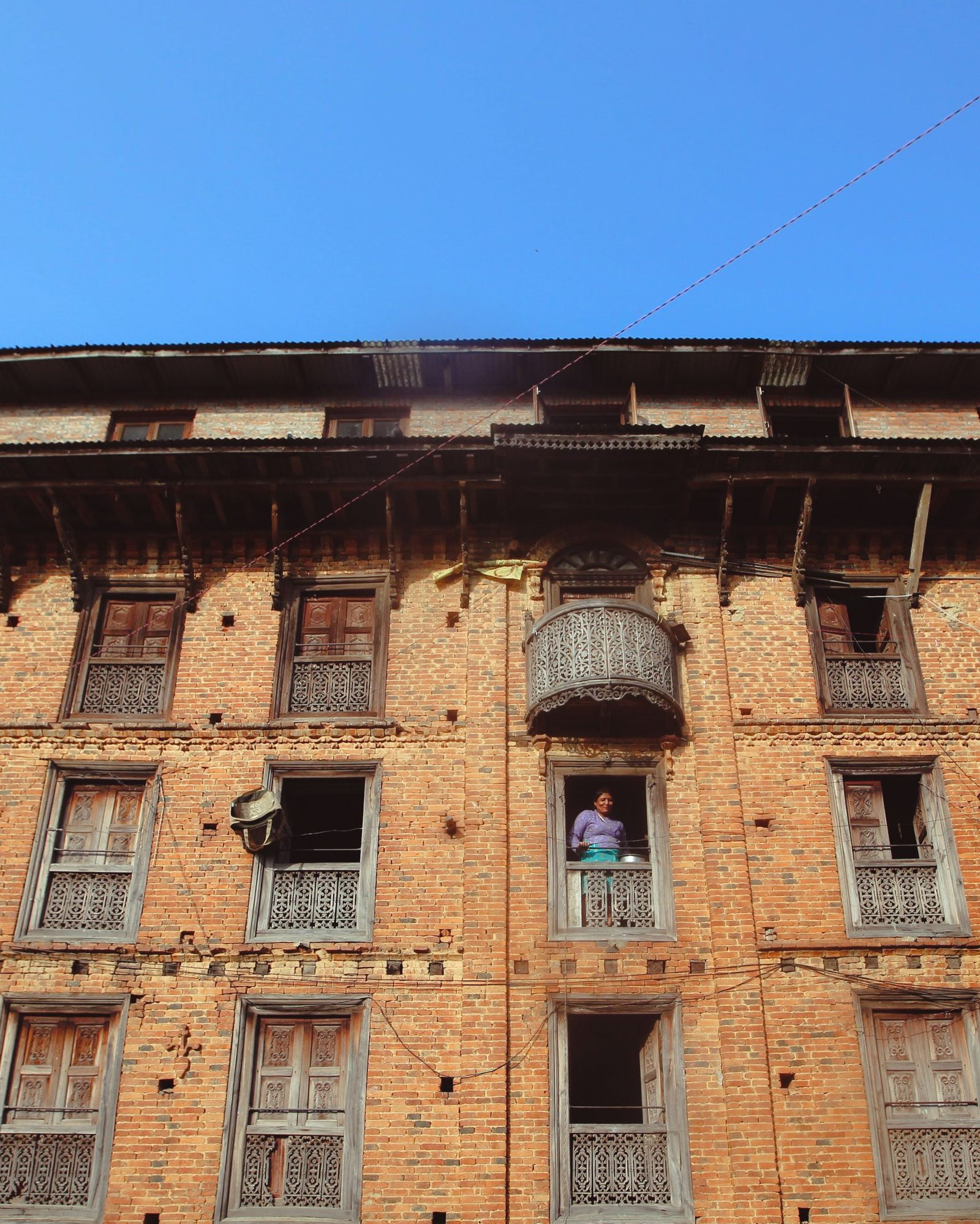 Immeuble ancien en brique à Albi, volets bois défraîchis et balcon en fer forgé